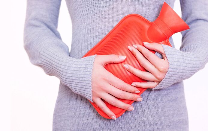Applying a heating pad to the stomach helps a woman relieve symptoms of cystitis.